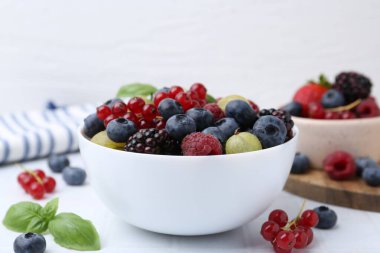 Farklı olgun, sulu böğürtlen ve fesleğen beyaz fayanslı masada, yakın plan.