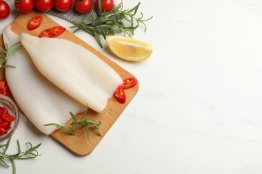 Çiğ mürekkep balıkları ve ürünler beyaz masada, düz yerde. Metin için boşluk