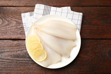 Ahşap masada limonlu çiğ mürekkep balıkları.