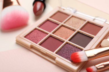 Renkli göz falı paleti, ruj, makyaj fırçası ve renk arkaplanı uygulayıcı, yakın plan