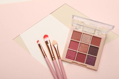 Renkli göz falı paleti ve renk arkaplanı üzerine makyaj fırçaları, düz yatış