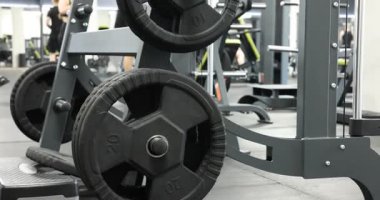 Spor salonunda halter disklerle dur, kamera yukarı çıkıyor.