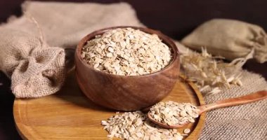 Tabaktaki yulaf gevreği, kaşık, çuval bezi ve çiçekleri masaya koyun, yakın plan. Kamera içeri giriyor.