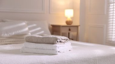 Kadın evdeki yatağa temiz havlu sepeti koyuyor, yakın plan.