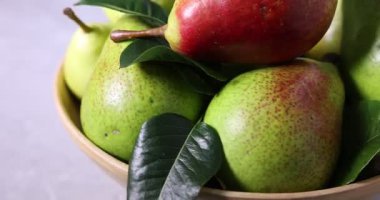 Taze armutlar ve yeşil yapraklar masada, yakın plan.