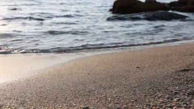 Güzel dalgalı deniz, taşlar ve kumlu sahil, yakın çekim.