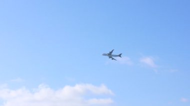 Bulutlu, alttaki manzaralı güzel mavi gökyüzünde uçan bir uçak. Kamera sola hareket ediyor