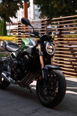 Bir tane modern siyah motosiklet açık hava yolunda park edilmiş.