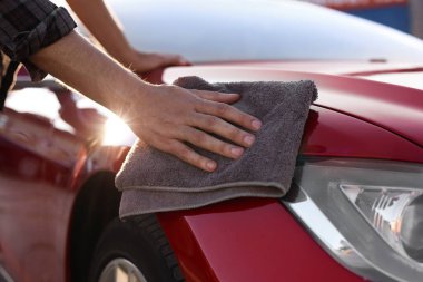 Dışarıdaki gri mikrofiber bez parçasıyla araba silen adam, yakın plan.