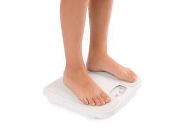 Küçük çocuk beyaz arka planda terazide duruyor, yakın plan.