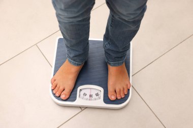 Küçük çocuk kapalı alanda, manzaranın üstünde duruyor.