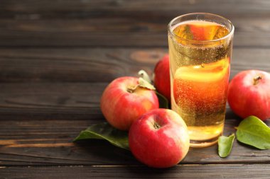 Cam, elma ve yeşil yapraklı nefis elma şarabı ahşap masada, yakın plan. Metin için boşluk