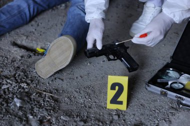 Adli tıp uzmanı olay yerinde çalışıyor. Terk edilmiş binanın içinde bir ceset var. Yakın plan.