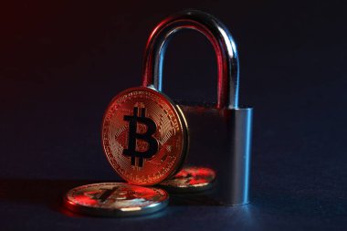 Bitcoinler ve asma kilit mavi arkaplanda kırmızı ışıkta, yakın plan