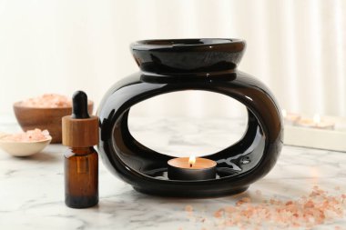 Aroma lambası yanan mum, deniz tuzu ve temel yağ beyaz mermer masa üzerinde, yakın çekim