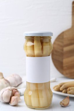 Beyaz fayanslı masada kuşkonmaz ve sarımsak turşusu.