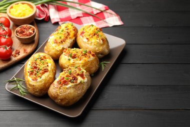 Siyah ahşap masada lezzetli fırınlanmış patatesler, yazı için yer.