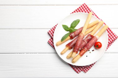 Lezzetli Grissini çubukları prosciutto, biber, domates ve fesleğen ile beyaz ahşap masa, üst manzara. Metin için boşluk