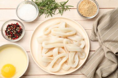 Ahşap masada pişmemiş mürekkep balığı halkaları, baharatlar, yumurta sarısı ve ekmek kırıntıları.