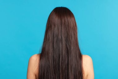 Açık mavi arka planda saçı zarar görmüş bir kadın.