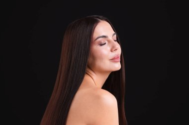 Siyah arka plandaki laminasyon prosedüründen sonra güzel düz saçlı bir kadın.