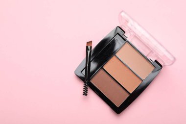 Renkli göz farı paleti ve pembe arka planda makyaj fırçası, üst manzara. Metin için boşluk