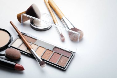 Göz falı paleti, diğer kozmetik ürünler ve beyaz arka planda fırçalar, yakın plan. Metin için boşluk