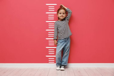 Boyunu mercan duvarının yanında ölçekle ölçen tatlı küçük bir kız.