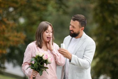 Nişan yüzüklü bir adam kız arkadaşına dışarıda evlenme teklif ediyor.