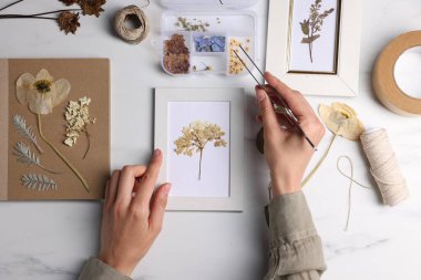 Beyaz mermer masa, üst manzara, resim çerçevesi içine kuru çiçekler koyan kadın