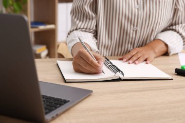 Ofisteki ahşap masada iş planlayıcısı kullanan kadın, yakın plan.