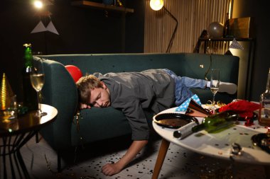 Adam partiden sonra dağınık bir odada kanepede akşamdan kalma.