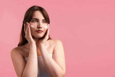 Yüzünde pembe arka planda krem olan güzel bir kadın. Metin için boşluk