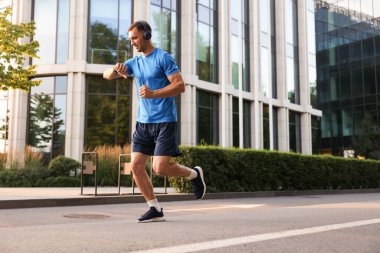 Adam açık havada koşarken fitness izleyicisini kontrol ediyor, metin için boşluk