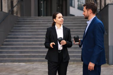 Paket kahve. Açık hava binası yakınında kağıt bardak içen iş adamları, metin için yer