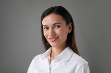 Gri arka planda kendine güvenen bir iş kadınının portresi