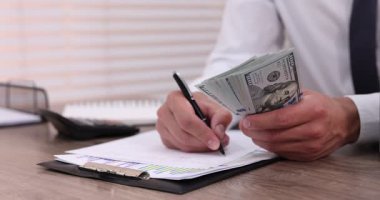 Ahşap masada dolar sayan adam, yakın plan.