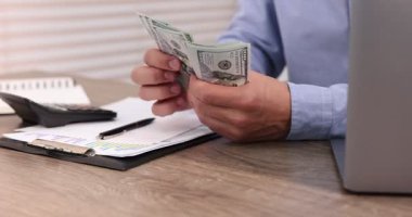 Ahşap masada dolar sayan adam, yakın plan.