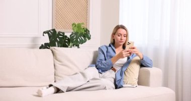 Akıllı telefonlu bir kadın klimayı açıyor ve evde kızına sarılıyor.