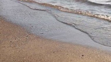 Güzel dalgalı deniz ve kumlu sahil, yakın çekim. Kamera hareket ediyor