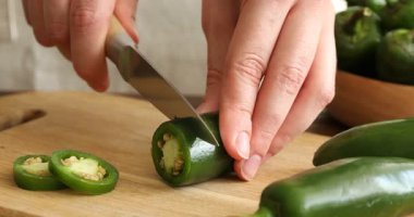 Ahşap masada yeşil biber kesen kadın, yakın plan.