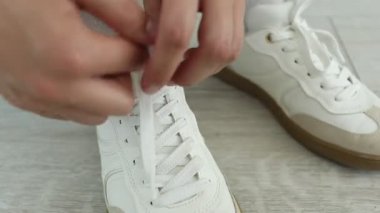 Beyaz spor ayakkabı bağcığı bağlayan kadın, yakın plan.