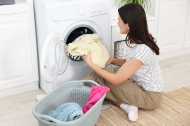Çamaşır makinesinden çamaşırları çıkaran kadın.