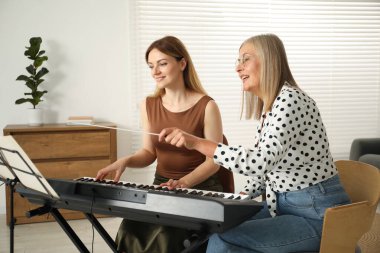 Öğretmenim kadınlara evde piyano çalmayı öğretiyor.