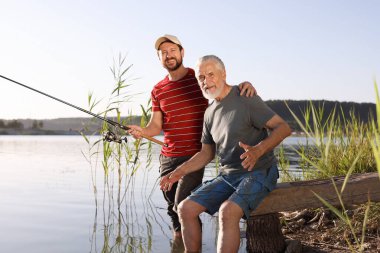 Yaşlı babası ve mutlu oğlu nehirde birlikte balık tutuyorlar.