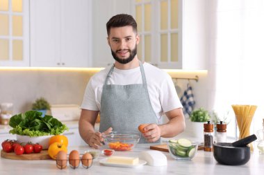 Mutfaktaki masada yemek pişiren gülümseyen adam.