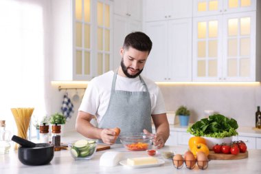 Mutfaktaki masada yemek pişiren gülümseyen adam.