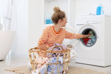 Kirli çamaşırları çamaşır makinesine koyan kadın.