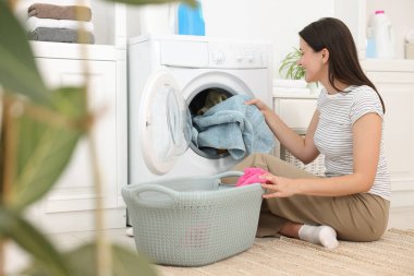 Çamaşır makinesinden çamaşırları çıkaran kadın.