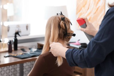 Profesyonel kuaför müşteriyle kuaförde çalışıyor.